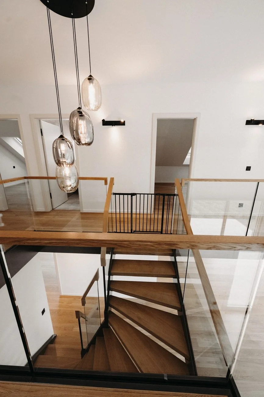 Escalier en bois, garde-corps vitrés et suspensions dans une réalisation du groupe